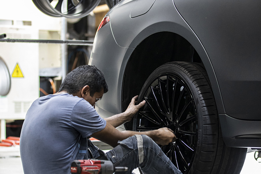 Technician inspecting a genuine Vossen wheel]